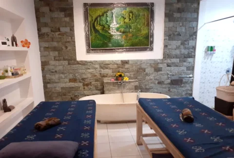 Private couple treatment room with two massage beds and a stone bathtub