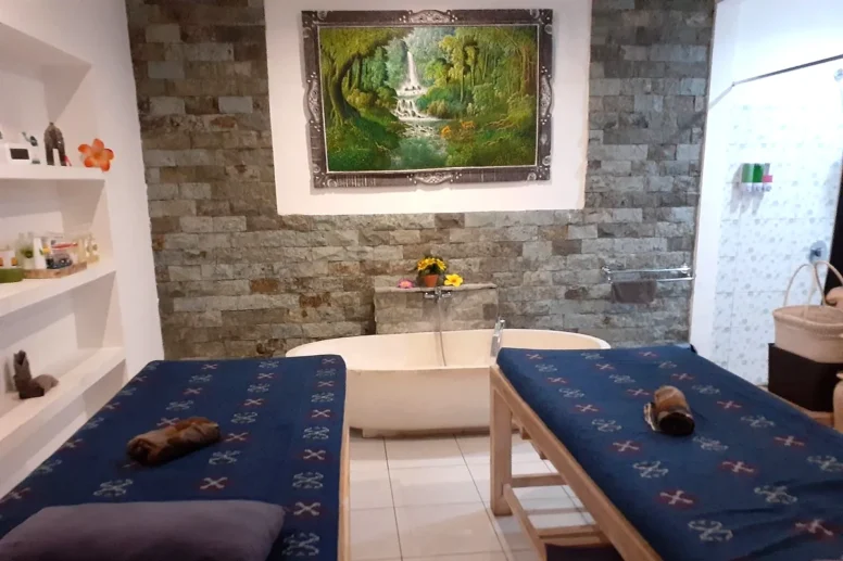 Private couple treatment room with two massage beds and a stone bathtub
